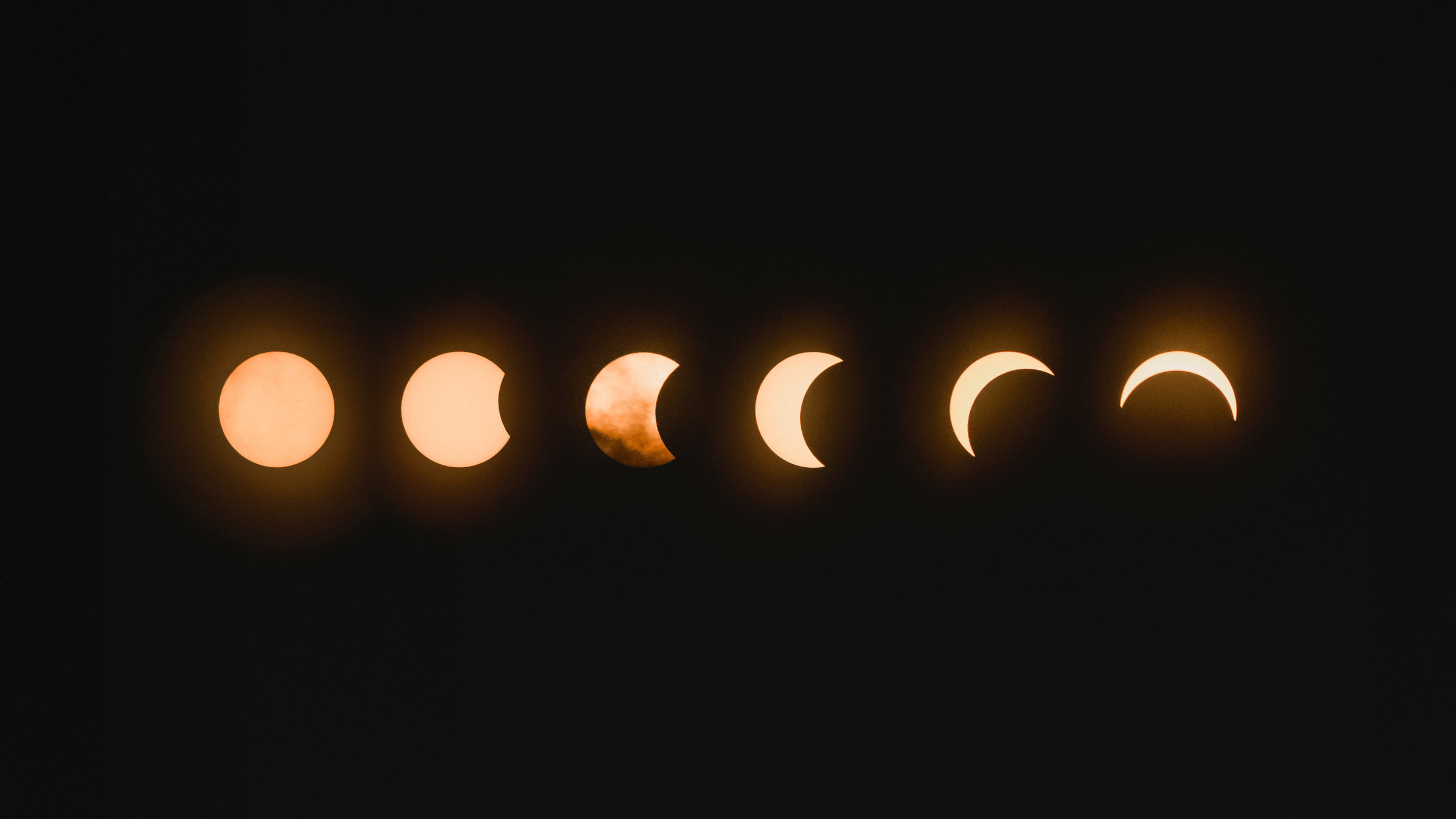 Sequence of solar eclipse phases showcasing the gradual obscuration of the sun by the moon against a dark background.