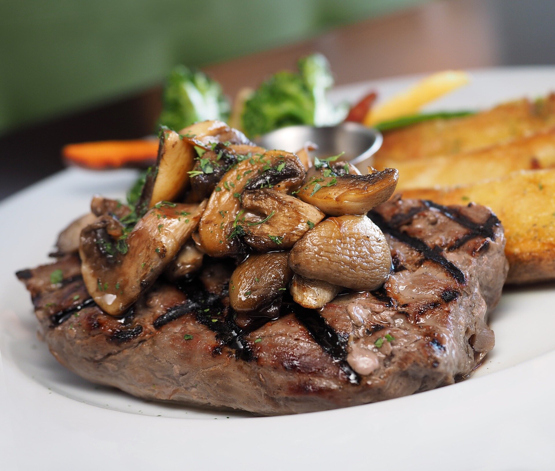 steak-1083567_1920 Grilled steak topped with sautéed mushrooms, served with broccoli, carrots, and crispy potato wedges on a white plate.